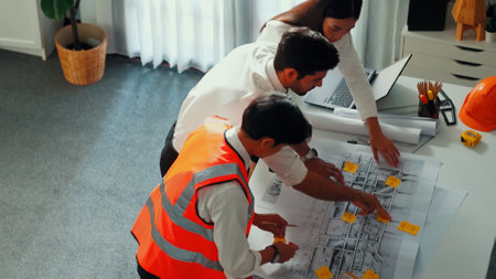 Top view of skilled architect engineer team looking at blueprint together. Aerial view of smart...