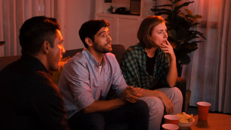 Top view of caucasian father and relaxed mother watching movie while eating snack with friend. Happy family with colleague looking at television while dad hold snack bowl at living room. Convocation.の写真素材