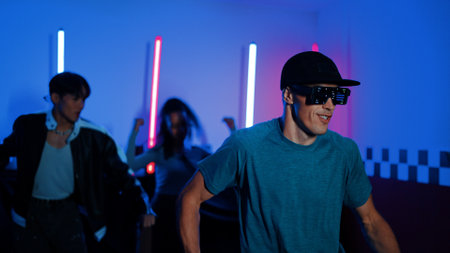 Skilled break dancer dancing in front of camera while diverse friend moving to pop or hip hop music...