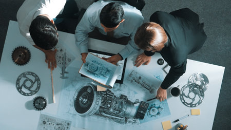 Top down view of skilled engineer working together while looking at jet engine. Aerial view of smart designer or diverse technicians brainstorming while looking at electronic generator. Alimentation.の写真素材