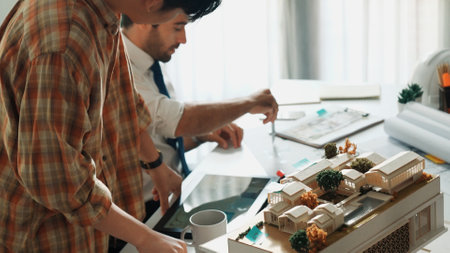 Smart architect engineer inspect house model while happy project manager walking and holding blueprint and asking about building construction. Group of diverse engineer working together. Alimentation.の写真素材