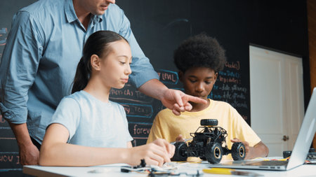 Caucasian teacher talking about electric tool while student fixing robotic model on table with electronic equipment placed. Diverse academic children learning about main board structure. Edification.の写真素材