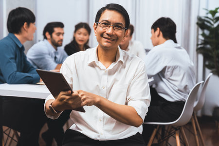 Confidence and happy smiling businessman portrait with background of his colleague and business team working in office. Office worker teamwork and positive workplace concept. Prudentの写真素材