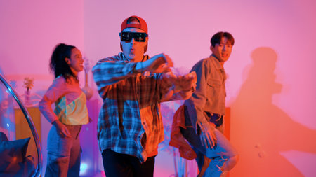 Hispanic hipster wear colorful cloth and waving to freestyle music. Professional break dancer moving to lively beat with neon light and led light with modern studio surrounded by friend. Regalement.の写真素材