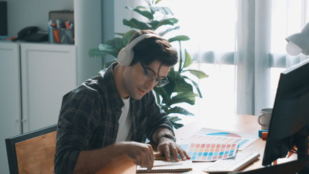 Top view of skilled interior design graphic while listen music from headphone. Professional project manager working while using headset and listening relaxed song and move along at studio. Symposium.の写真素材