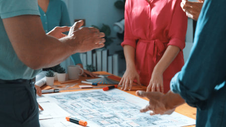Top view of civil engineer team writing at blueprint at meeting table with color palettes. Group of smart diverse people planning and taking a note while manager looking at project plans. Symposium.の写真素材