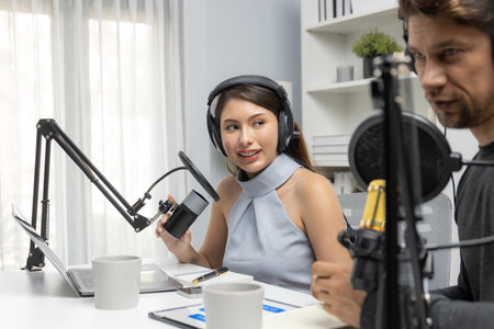 Host channel broadcasters discussing together, making advice for problem in live streaming with listeners surrounded sets of live streaming on radio talking show at comfy modern workplace. Postulate.の写真素材