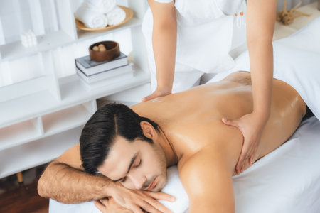 Caucasian man customer enjoying relaxing anti-stress spa massage and pampering with beauty skin recreation leisure in day light ambient salon spa at luxury resort or hotel. Quiescentの写真素材
