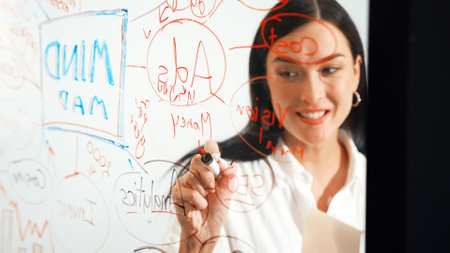 Closeup image of young beautiful businesswoman presenting marketing project while writing on glass...