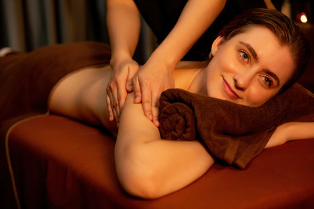 Caucasian woman customer enjoying relaxing anti-stress spa massage and pampering with beauty skin recreation leisure in warm candle lighting ambient salon spa at luxury resort or hotel. Quiescentの写真素材