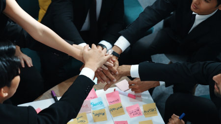 Top view of business people putting hands together and clapping hands to celebrate successful project while using kanban task board to manage time. Startup team stacking hands together. Directorate.の写真素材