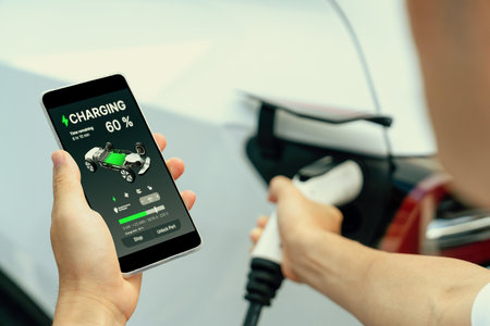 Hand insert EV charger plug into electric vehicle to recharge EV car, battery status display on...
