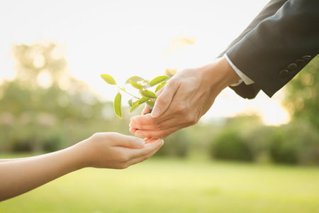 Businessman handing plant or sprout to young boy as eco company committed to corporate social responsible, reduce CO2 emission and embrace ESG principle for sustainable future.Gyreの写真素材