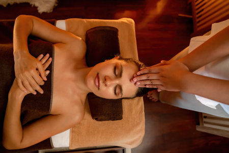 Caucasian woman enjoying relaxing anti-stress head massage and pampering facial beauty skin recreation leisure in warm candle lighting ambient salon spa in luxury resort or hotel. Quiescentの写真素材
