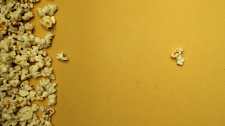Slow motion shot of popcorn was throwing with yellow background. Fresh movie popcorn moving and...