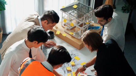 Top view of skilled architect engineer team inspect house model while project manager hold blueprint...
