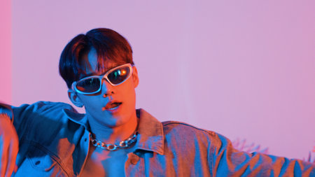 Close up of asian street dancer moving to pop music with neon light while diverse friend sitting and...