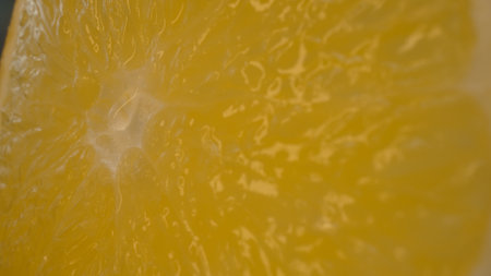 The macro photography of a sliced orange with vibrant orange color and visible in the juicy flesh of the citrus fruit. The flesh of the orange appears plump, hinting at its juiciness. Comestible.の写真素材