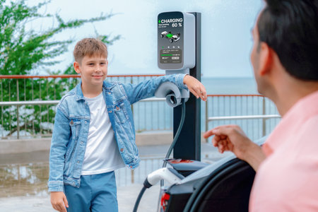 Family road trip vacation traveling by the sea with electric car, father and son recharge EV car...