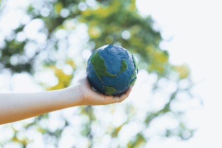 Young boys hand holding planet Earth globe at natural park background as Earth day to save this planet with ESG principle and environment friendly energy for brighter future. Gyreの写真素材