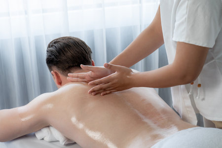 Caucasian man customer enjoying relaxing anti-stress spa massage and pampering with beauty skin recreation leisure in day light ambient salon spa at luxury resort or hotel. Quiescentの写真素材