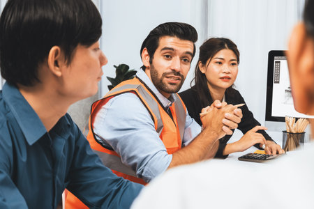 Diverse group of civil engineer and client working together on architectural project, reviewing construction plan and building blueprint at meeting table. Prudentの写真素材