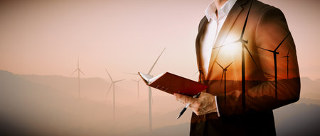Double exposure graphic of business people working over wind turbine farm and green renewable energy worker interface. Concept of sustainability development by alternative energy. udsの写真素材