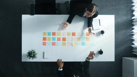 Top view of professional business people making agreement and brainstorm marketing idea or plan by using colorful sticky notes on table with coffee and paper placed on at meeting room. Directorate.の写真素材