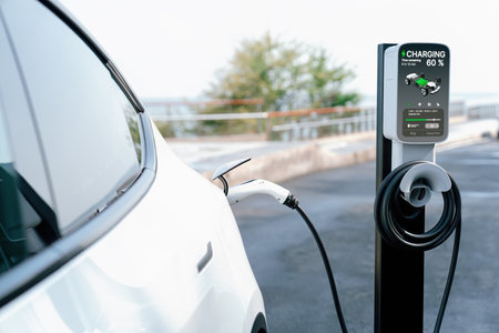 Electric car recharging battery at outdoor EV charging station for road trip or car traveling by the seascape, alternative and sustainable energy technology for eco-friendly car. Perpetualの写真素材