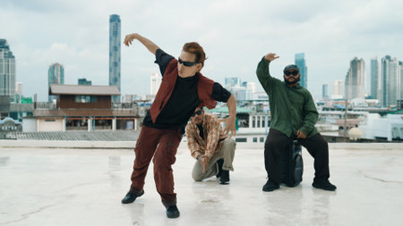Group of professional hip hop dancer practice break dance on roof top. Skilled choreographer show freestyle movement while friend encourage, cheer,clap hands. Outdoor sport 2024. Hiphop.の写真素材
