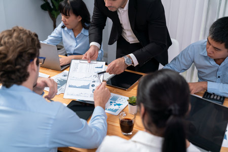 Diverse group of business analyst team analyzing financial data report paper on office table. Chart and graph dashboard by business intelligence analysis for strategic marketing planning Habilimentの写真素材