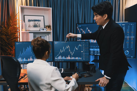 Trading business partners discussing on dynamic stock exchange statistic on pc screens taking note on paper, comparing with high or low point on currency graph at night neon modern office. Infobahn.の写真素材