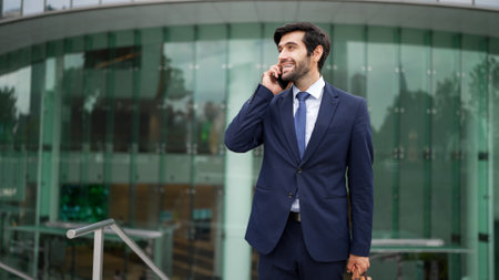 Skilled caucasian project manager calling phone while walking at city with blurred background. Skilled businessman using smart phone talking to project manager with blurred background. Exultant.の写真素材