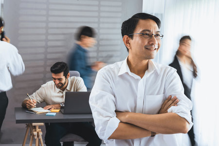 Confidence and happy smiling businessman portrait with blur motion background of his colleague and business team working in office. Office worker teamwork and positive workplace concept. Prudentの写真素材