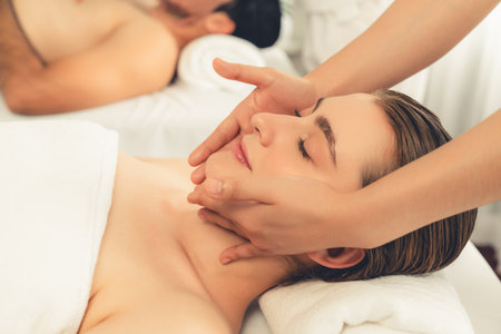 Caucasian couple enjoying relaxing anti-stress head massage and pampering facial beauty skin recreation leisure in dayspa modern light ambient at luxury resort or hotel spa salon. Quiescentの写真素材