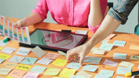 Close up of smart manager hand pointing at tablet display logo at meeting table with sticky notes...