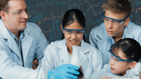 Girl looking at beaker while doing experiment at blackboard with chemistry theory in STEM class. teacher and group of highschool student with mixed races doing science activity together. Edification.の写真素材