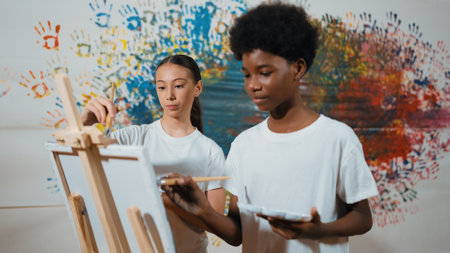 Diverse happy children paint canvas together with colorful stained wall. Smart multicultural student...