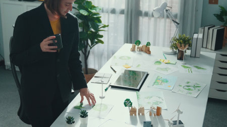 Skilled project manager walking around meeting table with green business element. Caucasian business woman looking at element on table represent renewable energy or sustainable energy. Alimentation.の写真素材
