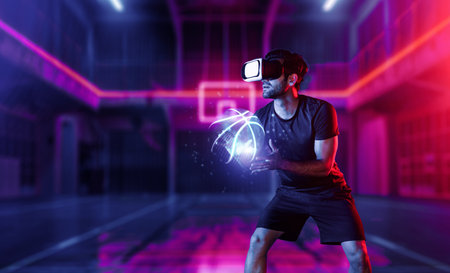 Caucasian sport person playing basketball at neon sport stadium while wearing casual cloth and virtual reality glasses. Athlete holding basketball hologram while standing at sport arena. Deviation.の写真素材