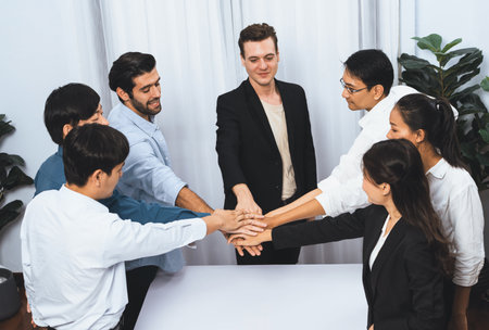 Group of diverse office worker join hand together in office room symbolize business synergy and strong productive teamwork in workplace. Cooperation and unity between business employee. Prudentの写真素材