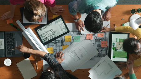 Top down view of manager writing project plan and sitting at meeting. Aerial view of business people planning and sharing idea about house construction at table with laptop and equipments. Symposium.の写真素材