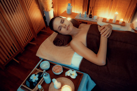Caucasian woman customer enjoying relaxing anti-stress spa massage and pampering with beauty skin recreation leisure in warm candle lighting ambient salon spa at luxury resort or hotel. Quiescentの写真素材