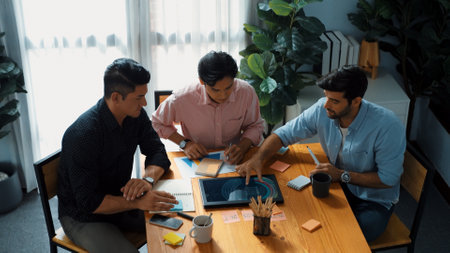 Top view of team working together to brainstorm idea while project manager talking to phone at meeting room. Male leader calling investor and present plan while team discussing strategy. Convocation.の写真素材