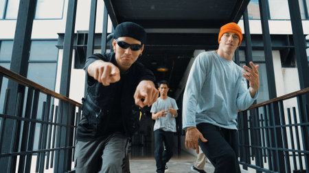Group of smart hipster walking at modern bridge while pose at camera. Attractive handsome street dancer group looking at camera while dancing. Active, cool. Outdoor sport 2024. Hiphop.の写真素材