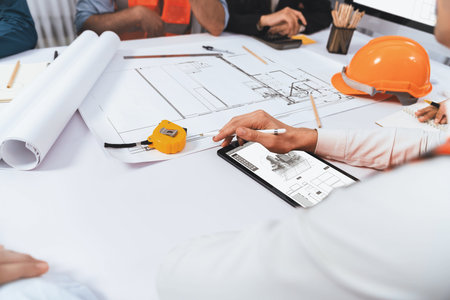 Diverse group of civil engineer and client working together on architectural project, reviewing construction plan and building blueprint at meeting table. Prudentの写真素材