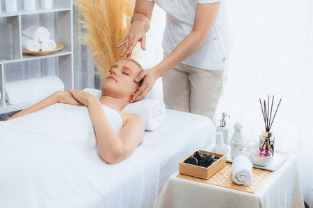 Caucasian woman enjoying relaxing anti-stress head massage and pampering facial beauty skin recreation leisure in dayspa modern light ambient at luxury resort or hotel spa salon. Quiescentの写真素材
