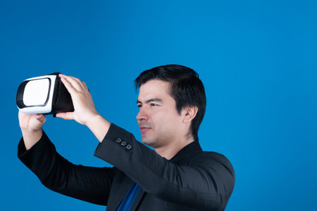 Profile smiling businessman holding VR headset looking metaverse posing portrait isolated blue background futuristic technology in virtual reality in meta finance business digital data. Contrivance.の写真素材