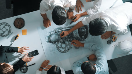 Top down aerial view of smart engineer team working together to design turbine engine. Professional technician discussing about jet engine construction while pointing at part of engine. Alimentation.の写真素材