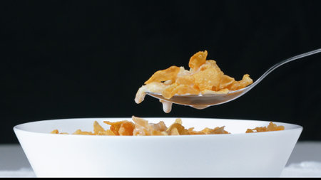Side view of white bowl with yellow cereal and milk prepare for eating breakfast with separated...